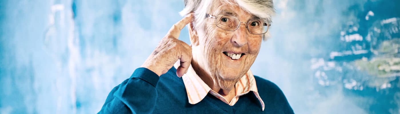 older woman points at head