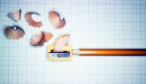 pencil in pencil sharpener and shavings on graph paper