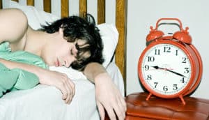teen boy sleeping next to alarm clock