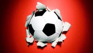 soccer ball busts through red paper