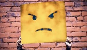 holding up angry face sign (negative feelings on surveys concept)