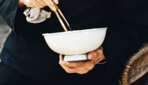 elderly woman holds white bowl