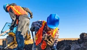 two muddy men look for mammoth bones