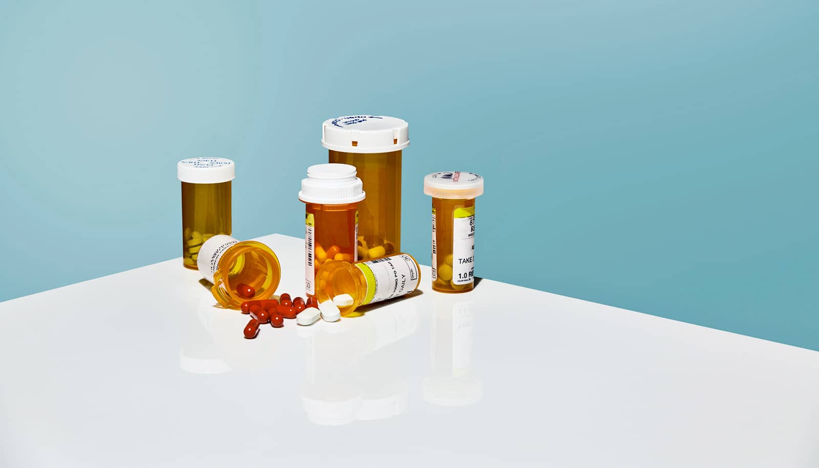 pills on a white table against blue (opioids, drug manufacturers)