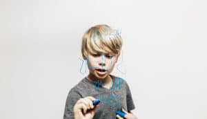 boy does math in blue on glass