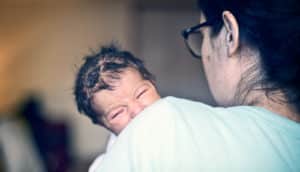 crying baby (colic) on mom's shoulder