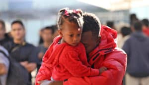 Haitian refugee man holds toddler girl