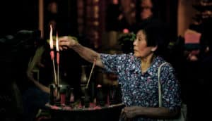 woman lights joss sticks in temple
