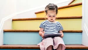 young girl reading iPad on stairs (speech recognition apps and literacy concept)