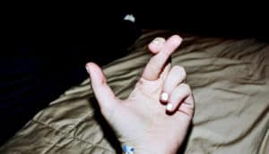 fingers crossed over bed (lying concept)