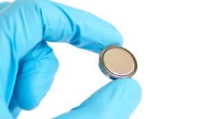 hand in blue glove holds aluminum battery