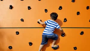 boy on orange climbing wall