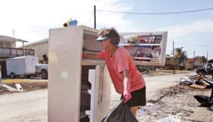 woman cleans fridge after hurricane - housing recovery