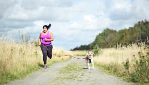 woman runs with dog - exercise and happiness