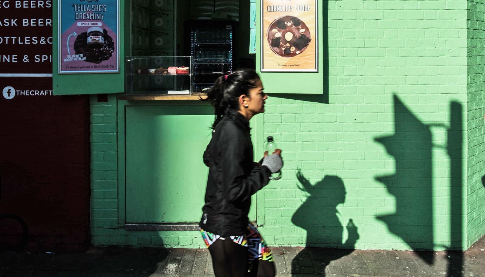 woman jogs by green wall