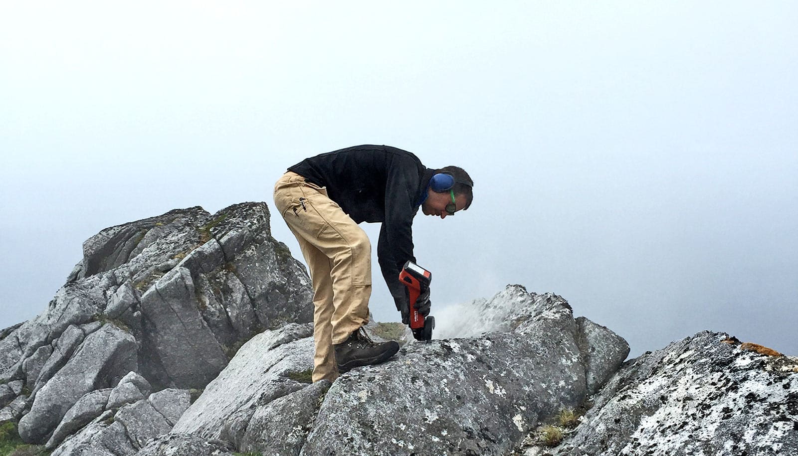 geologist bends to drill into rock