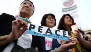 activists hold "peace with north korea" sign