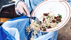 scraping plate into trash (food waste concept)