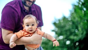 dad holds baby in orange shirt