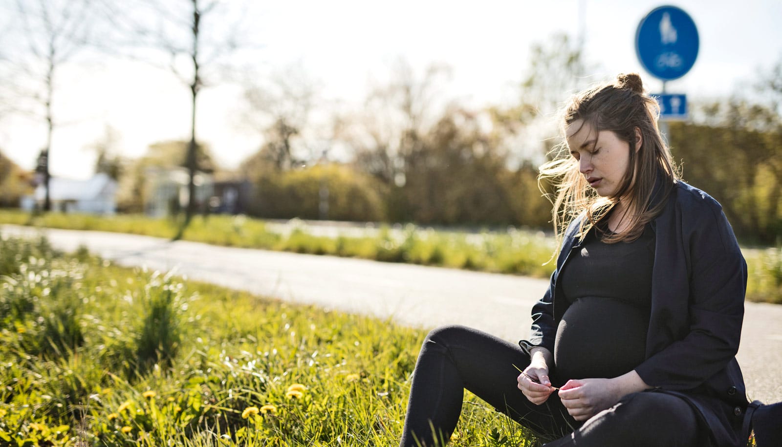 pregnant woman sits on side of path - opioid treatment programs