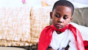 young boy in cape on couch (suspension concept)