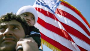 child on father's shoulders with US flag in the background