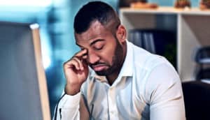man rubbing eyes at the office (sleep deprivation concept)