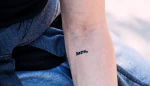 tattoo on arm says "here"
