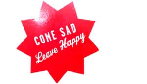 red sticker says "come sad leave happy"
