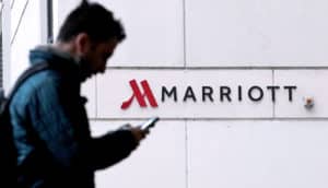 man with phone in front of Marriott sign on building
