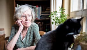 pensive older woman looks at cat