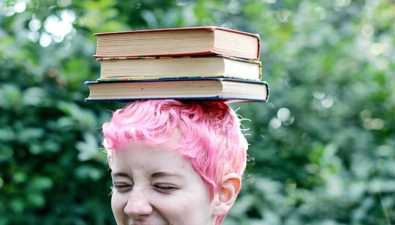 books on head of teen with pink hair