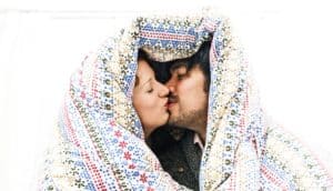 couple kisses under blanket