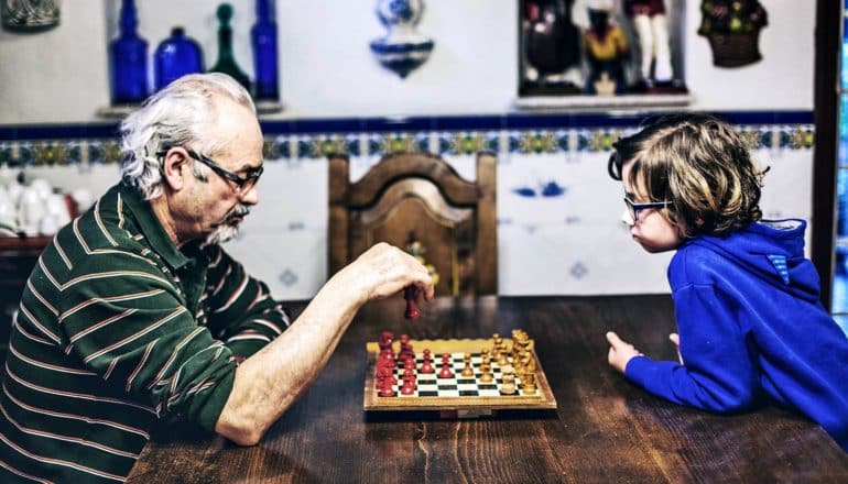 grandpa and grandson playing chess (extended families concept)