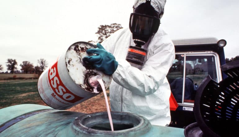 person in mask pours pesticide liquid