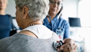 medical worker holds stethoscope on woman's back