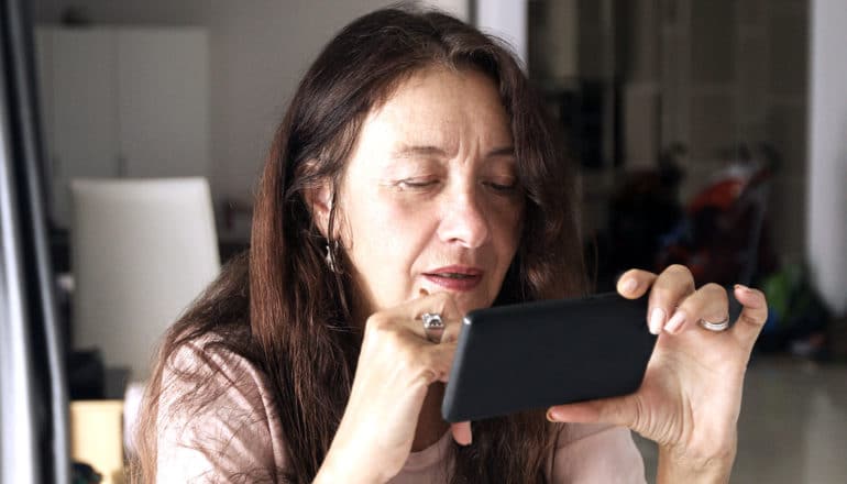 woman looking at phone (fake news concept)
