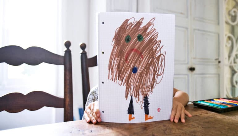 child behind drawing of brown sad blurry person