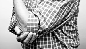 man holds elbow in pain - osteoarthritis