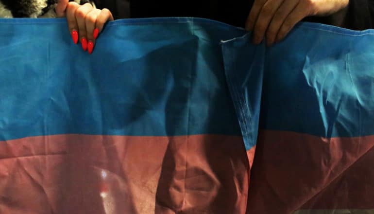 hand with hot pink nails holds trans flag