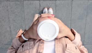 high angle shot of woman in pink holding disposable coffee cup