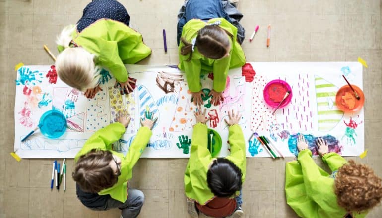 five kids in green smocks paint