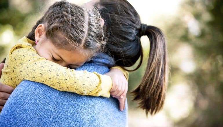 daughter hugs mother facing away