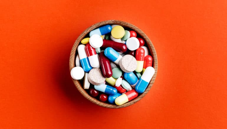 pills in a bowl on orange