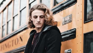 sad teen next to school bus