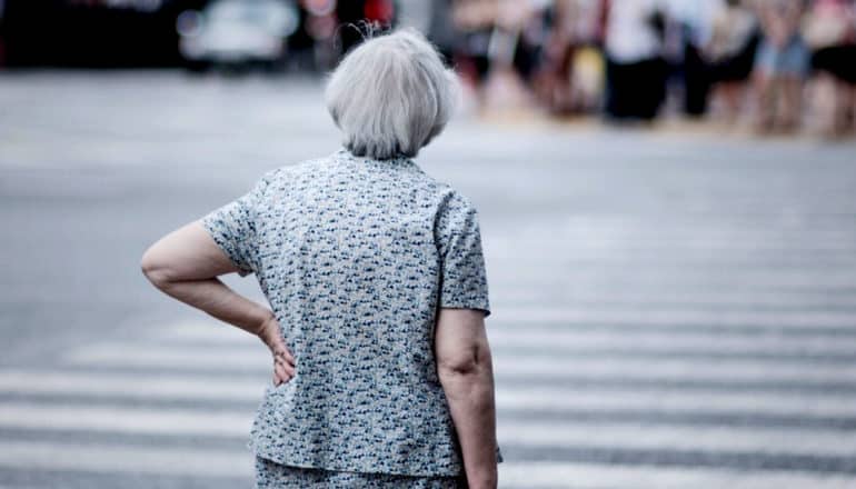 elderly woman with hand on hip at crosswalk