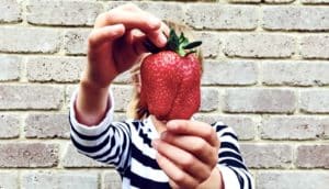 young girl holding strawberry