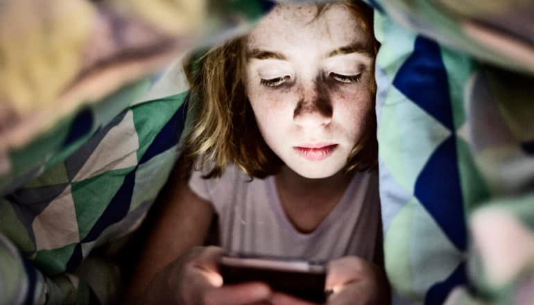 abuse hotlines - girl under blanket texting