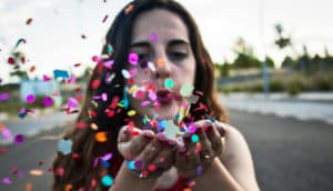 woman blows confetti from hands