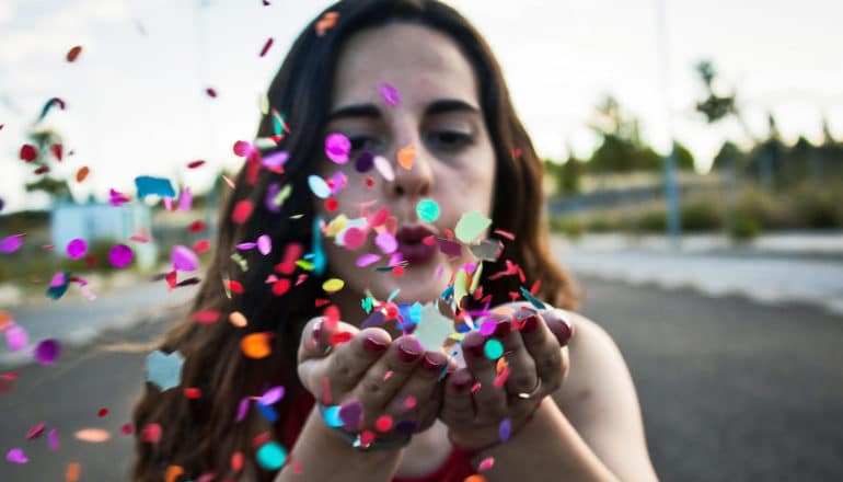 woman blows confetti from hands